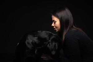 uma garota tem um cachorro labrador retriever nos braços. foto