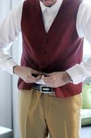 detalhe meio corpo close homem colete vermelho com camisa branca abrindo o colete ou fixando segurando o botão do colete. foto