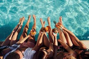 vista superior do grupo de jovens felizes que se divertem na piscina durante o dia foto