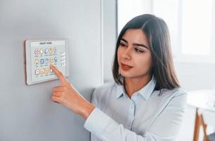 mulher está dentro de casa controlando tecnologia de casa inteligente foto