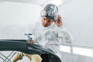 pintando o carro. homem de uniforme está trabalhando no auto serviço foto