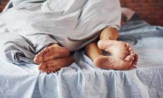 close-up vista dos pés do casal que dorme juntos no quarto na hora da manhã