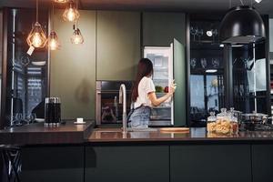 preparação de alimentos frescos. jovem morena linda em roupas casuais dentro de casa na cozinha durante o dia foto