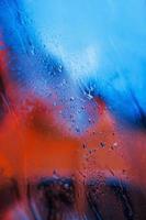 gotas de água no fundo de vidro neon. cores vermelhas e azuis