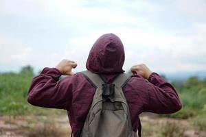 vista traseira do homem usa mochila e pano de capuz marrom, fique ao ar livre, aproveite os passeios pela natureza. conceito, viajar sozinho, feliz e liberdade viajar nas férias de férias. foto