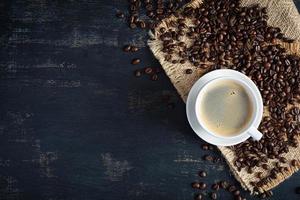 xícara de café com grãos de café em fundo escuro. caneca de café quente foto