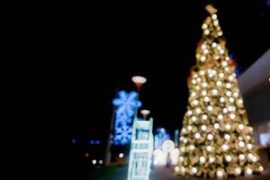 visão turva e bokeh da árvore de natal e decorar a frente de iluminação led do shopping na noite de natal na cidade urbana. foto