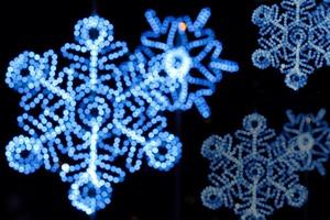led borrado e decorado com bokeh de iluminação azul natalina em forma de floco de neve na noite e fundo preto. foto