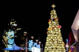 visão turva e bokeh da árvore de natal e decorar a frente de iluminação led do shopping na noite de natal na cidade urbana. foto