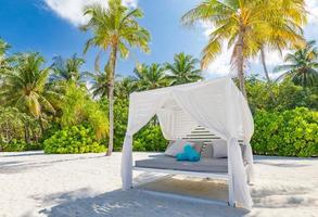 incrível fundo de férias de verão. cenário de luxo da praia com dossel de praia branca e espreguiçadeiras. relaxante ilha paradisíaca, luxuosa paisagem tropical. cena dos sonhos, praia da serenidade, copa do lounge foto