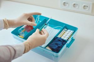 as mãos nas luvas médicas pegam a seringa da caixa de remédios foto