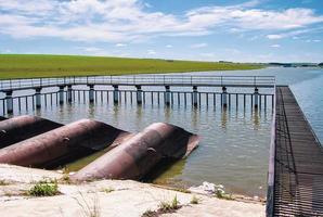 instalações de captação de água, rio, barragem, tubulações e plataforma de rede metálica no reservatório de água foto