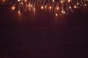 corda de guirlanda de natal com luzes quentes em fundo marrom escuro foto