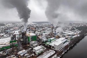 vista aérea panorâmica de inverno da fumaça dos canos de uma fábrica de produtos químicos ou empresa de carpintaria. conceito de poluição do ar e da água. foto