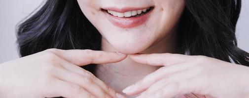 conceito de estomatologia, retrato parcial de menina com fortes dentes brancos, olhando para a câmera e sorrindo, dedos perto do rosto. closeup de jovem no dentista, estúdio, dentro de casa foto