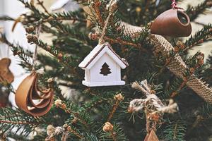 casa de brinquedo de madeira vintage na árvore de natal. enfeites de natal naturais para árvore de natal, desperdício zero foto