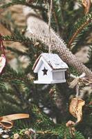 casa de brinquedo de madeira vintage na árvore de natal. enfeites de natal naturais para árvore de natal, desperdício zero foto