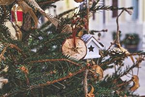 decorando a árvore de natal com pedaço de maçã seca, casa de brinquedo. enfeites de natal naturais para arvore de natal foto