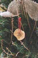 decorando a árvore de natal com pedaço seco de maçã com fita. enfeites de natal naturais para árvore de natal, desperdício zero foto