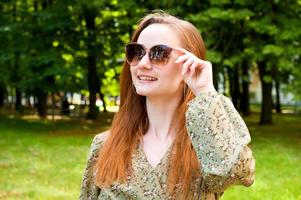 jovem linda em óculos de sol no parque no verão. retrato em close foto