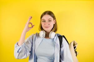 jovem mulher caucasiana mostrando sinal de mão ok retrato de estúdio em fundo amarelo foto