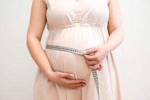 jovem grávida medindo o abdômen em crescimento. foto