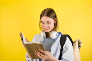 menina jovem estudante alegre na camisa azul com livro de leitura de mochila. educação no conceito de faculdade universitária do ensino médio. banner copyspace foto