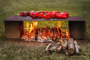 vista panorâmica de pimentões vermelhos assados na chapa de ferro quente ao ar livre com fogo aberto foto