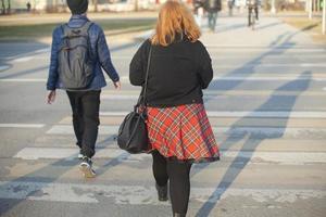 uma garota de saia vermelha caminha pela cidade. a garota e o cara estão andando na rua. foto