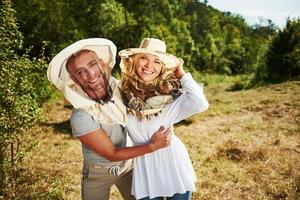 retrato de dois apicultores adoráveis. fica junto perto das colmeias. doce casal se abraçando foto