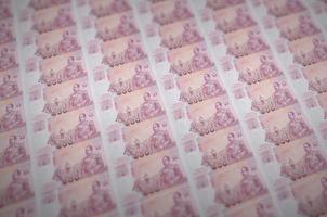 100 notas de baht tailandês impressas em transportador de produção de dinheiro ilegal. colagem de muitas notas falsas. conceito de trabalho de falsificadores foto