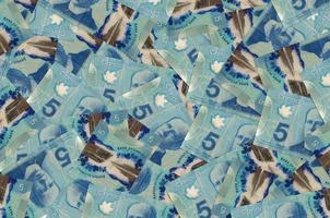 Notas de 5 dólares canadenses estão em uma grande pilha. fundo conceitual de vida rica foto