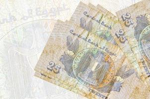 Notas de 25 piastras egípcias estão empilhadas no fundo de uma grande nota semitransparente apresentação abstrata da moeda nacional foto