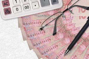Ventilador e calculadora de notas de 10 hryvnias ucranianos com óculos e caneta. empréstimo comercial ou conceito de temporada de pagamento de impostos foto