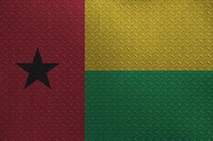 bandeira da guiné bissau retratada em cores de tinta na velha placa de metal escovado ou closeup de parede. banner texturizado em fundo áspero foto