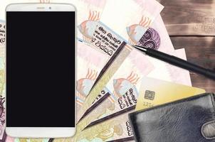 20 contas de rúpias do Sri Lanka e smartphone com bolsa e cartão de crédito. pagamentos eletrônicos ou conceito de comércio eletrônico. compras online e negócios com dispositivos portáteis foto