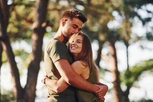 felizes juntos. abraçando um ao outro. lindo casal jovem se diverte na floresta durante o dia foto
