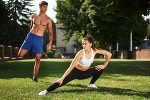 caras têm bons abdominais. homem e mulher têm dia de fitness na cidade durante o dia no parque foto