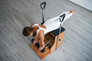 vista aérea. jovem desportiva confiante com tipo de corpo magro no centro saudável fazendo exercícios usando equipamentos especiais foto