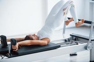 bom para a coluna. jovem desportiva confiante com tipo de corpo magro no centro saudável fazendo exercícios usando equipamentos especiais foto