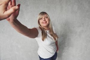 me dê seu high five. jovem mulher branca no estúdio em pé contra um fundo cinza foto