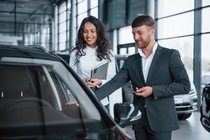 no bom humor. cliente do sexo feminino e empresário barbudo elegante moderno no salão de automóveis foto