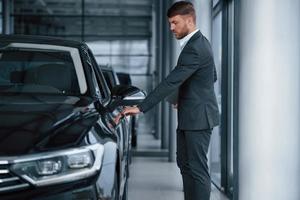 abrindo a porta. empresário barbudo elegante moderno no salão de automóveis foto