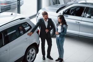 escolha perfeita. cliente do sexo feminino e empresário barbudo elegante moderno no salão de automóveis foto