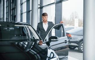 vamos ao trabalho. empresário barbudo elegante moderno no salão de automóveis foto