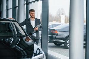 parece longe. empresário barbudo elegante moderno no salão de automóveis foto