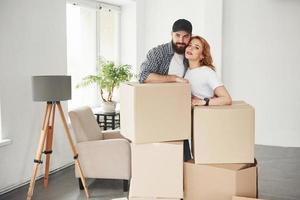 sala cheia de caixas. casal feliz juntos em sua nova casa. concepção de movimento foto