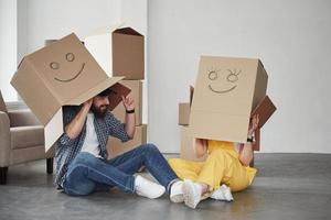 caixas com rostos sorridentes nele. casal feliz juntos em sua nova casa. concepção de movimento foto