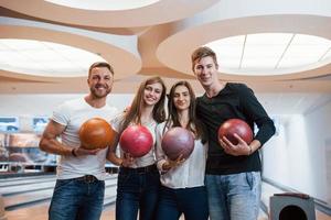 belas pessoas modernas sorrindo para a câmera. jovens amigos alegres se divertem no clube de boliche em seus fins de semana foto