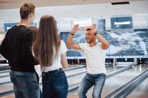 Ótimo jogo. jovens amigos alegres se divertem no clube de boliche em seus fins de semana foto